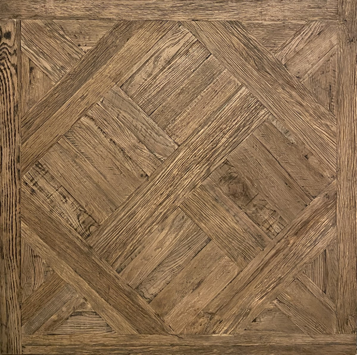Reclaimed oak flooring arranged in parquet squares with visible grain and wear
