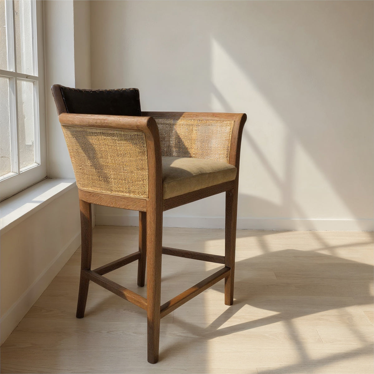 Counter chair with black leather seat, cane arm panels and oak frame