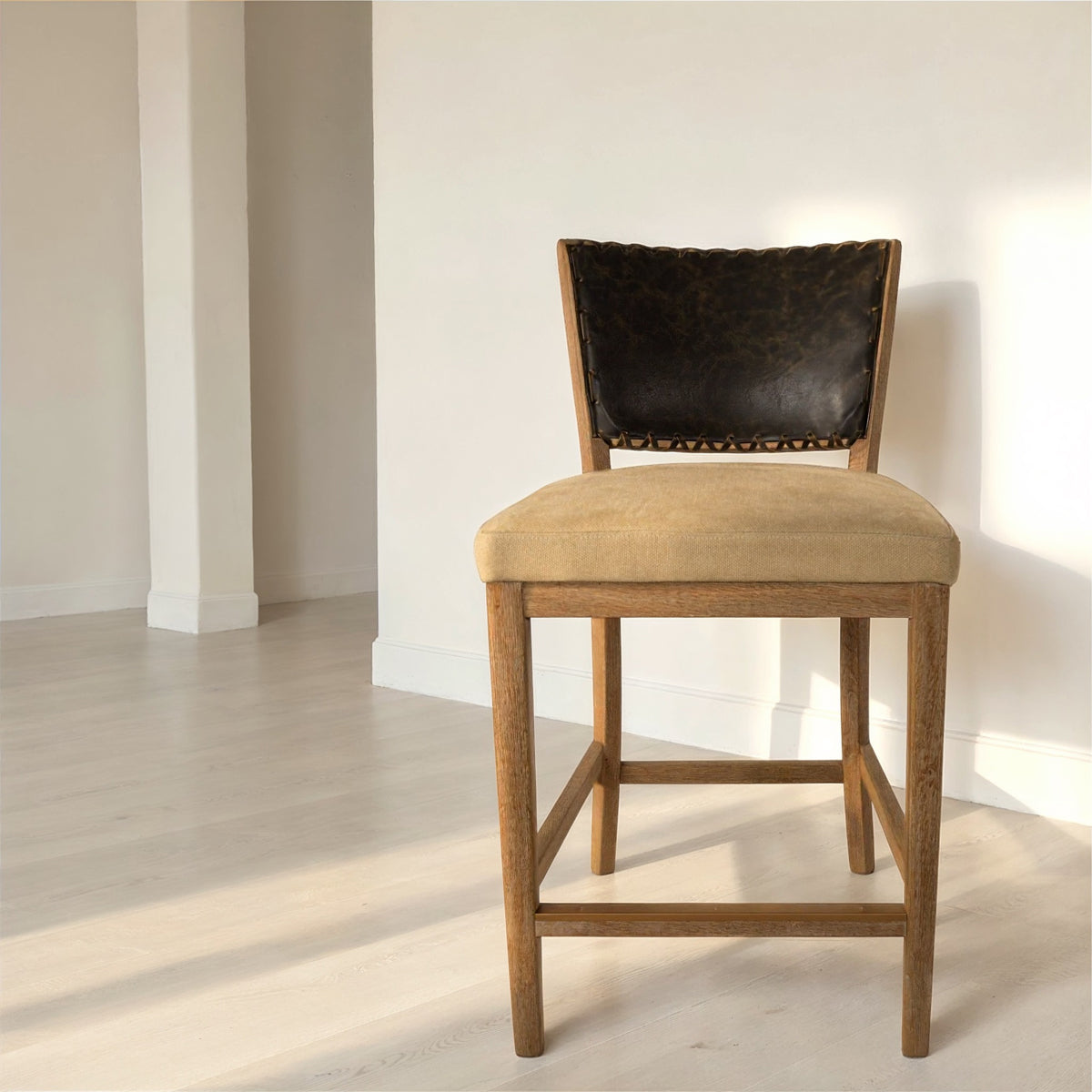 Armless counter chair with a black leather back and seat on an oak frame
