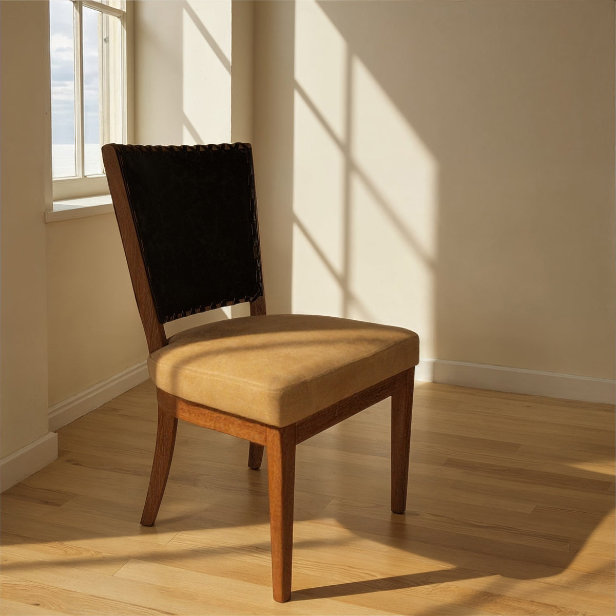 Side chair with a black leather back and upholstered seat on an oak frame