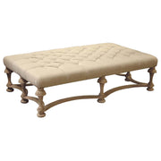 Long tufted linen ottoman on a natural birch frame with turned legs.