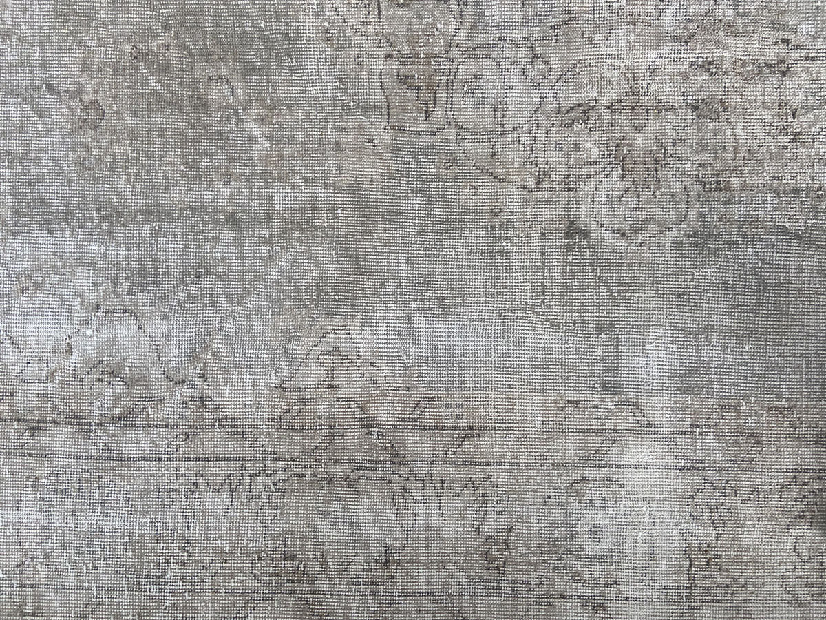 Heavily worn handwoven Turkish wool rug in cool, faded tones.