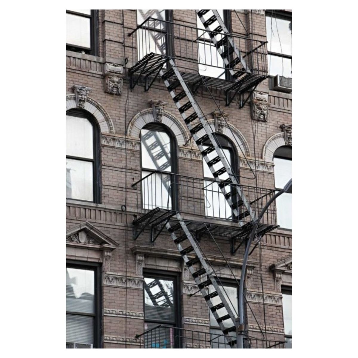 Photograph of a New York City fire escape on a brick facade, on metal